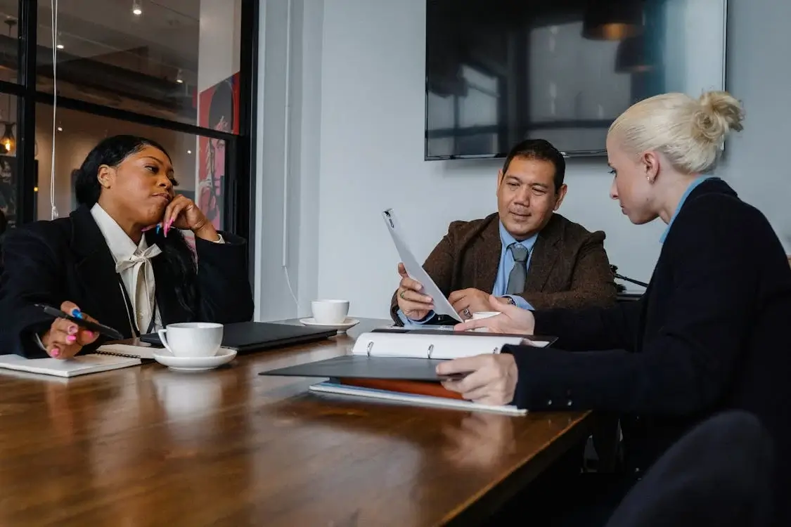 Three person wearing a formal attire and having a business meeting in an office setting.